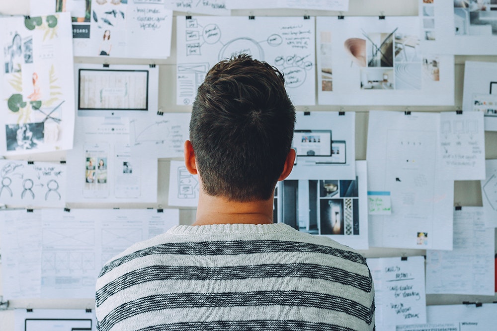 Image shows a man business planning in front of a whiteboard